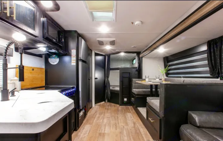 Modern RV rental interior featuring a full kitchen, dining booth, and cozy bunk beds. Ideal for family road trips.. Forest River Cherokee Grey Wolf 2022