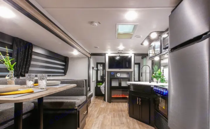 Spacious, modern RV rental interior featuring a comfortable dining booth, full kitchen, and living area with a TV and fireplace.. Forest River Cherokee Grey Wolf 2022