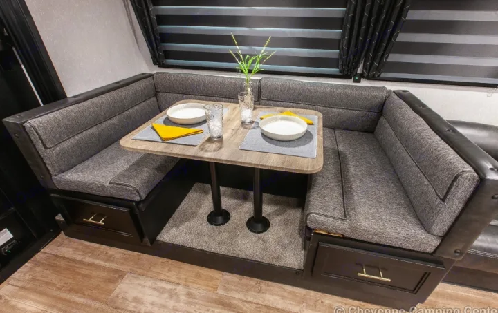 RV rental dinette featuring a U-shaped booth with grey cushions, a table set for two, and under-seat storage drawers.. Forest River Cherokee Grey Wolf 2022