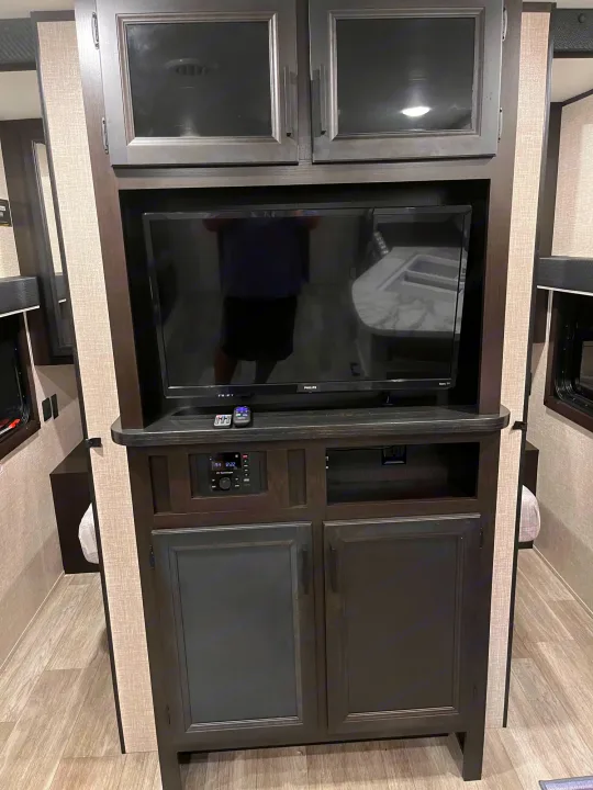 Modern RV rental interior: an entertainment center featuring a TV, RV stereo, and ample storage cabinets.. Jayco Jay Flight 2022