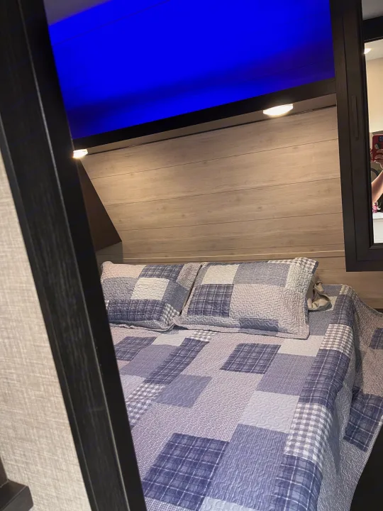 RV rental bedroom showing a patchwork quilt bed, wood headboard, and vibrant blue overhead lighting.. Jayco Jay Flight 2022