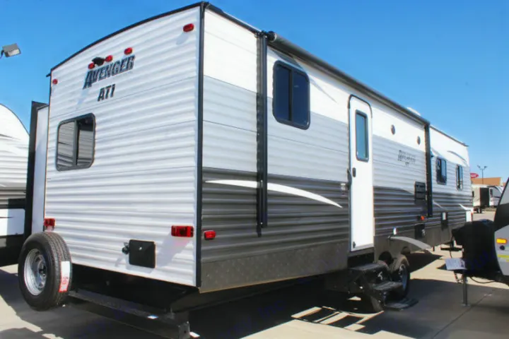 Exterior view of a modern Avenger ATI travel trailer, ideal for an rv rental. Shows the rear with a spare tire and side with an awning.. Avenger ATI 2020