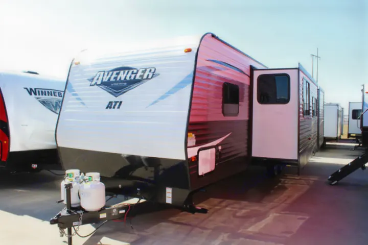 An Avenger ATI travel trailer with an open slide-out, featuring propane tanks, ideal for rv rental.. Avenger ATI 2020