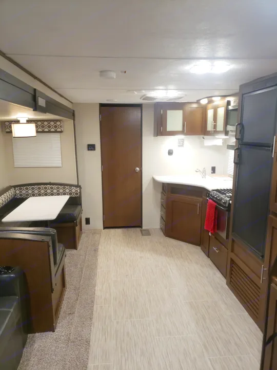 Inside an rv rental: a cozy dinette with patterned cushions, a full kitchen featuring a sink, stove, fridge, and ample cabinets.. Avenger ATI 2020