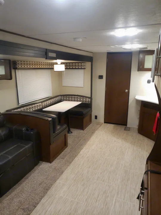 Spacious RV rental interior featuring a comfortable dinette, a couch, and a kitchen area with mixed flooring.. Avenger ATI 2020