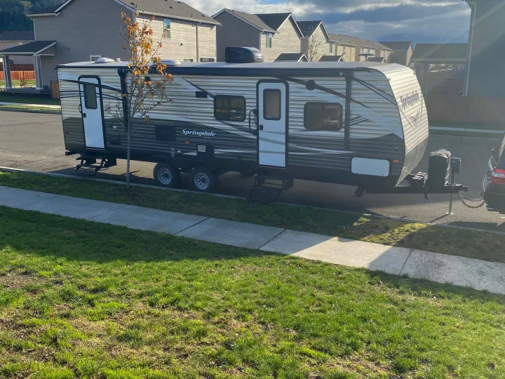 A Springdale travel trailer (RV rental) is parked on a residential street with houses in the background.. Keystone RV Springdale 2017