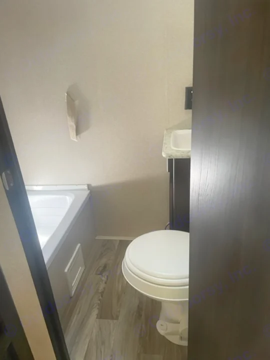 Inside an RV rental bathroom: a clean white toilet, a compact shower/tub combo, and wood-patterned flooring.. Keystone RV Springdale 2019