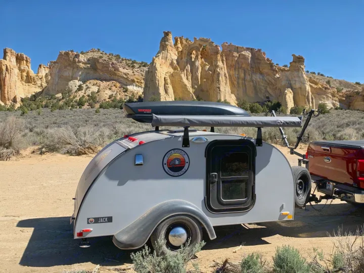 Teardrop RV rental, "Jack," parked in a desert landscape with towering rock formations. Ideal for outdoor adventures.. Little Guy Silver Shadow 2015