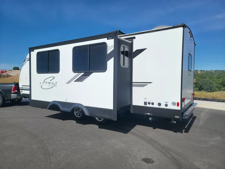 White Spirit Ultra-Lite travel trailer, with a slide-out extended, parked on asphalt. Perfect for your RV rental getaway!. Coachmen Spirit Ultra Lite 2021