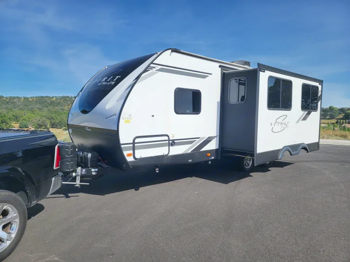 White and black Spirit Ultra Lite travel trailer connected to a black pickup truck, ready for RV rental adventures.. Coachmen Spirit Ultra Lite 2021
