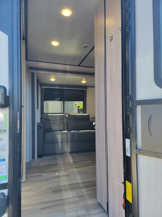 View inside an RV rental's cozy living space with light wood flooring, gray padded seating, wall lights, and a window.. Coachmen Spirit Ultra Lite 2021