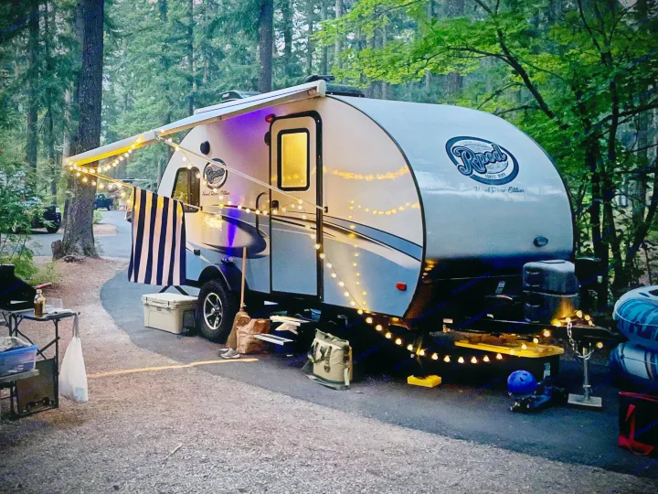 An R-pod travel trailer RV rental at a forest campsite, beautifully lit with string lights for a cozy evening.. R-Pod Hood River Edition 2017