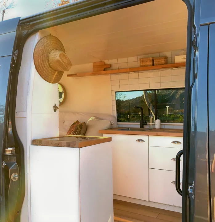 Explore in style! This cozy, converted van interior offers a modern kitchen and bed, perfect for your next RV rental.. Mercedes-Benz Sprinter 2016