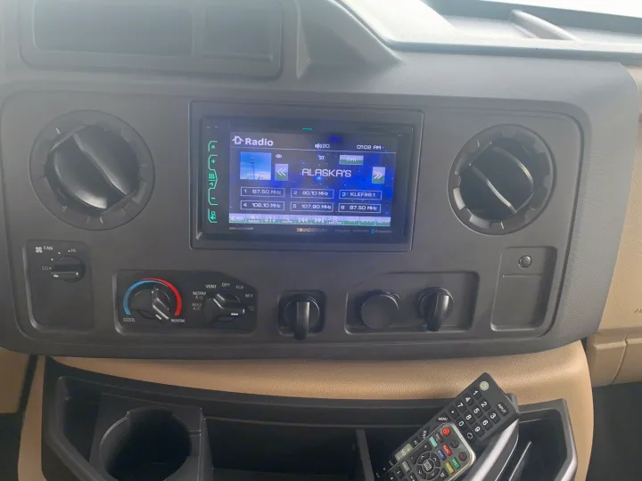 Dashboard of an RV rental with a Soundstream car radio playing Alaska's, air vents, climate controls, and a remote.. Jayco Redhawk 2020