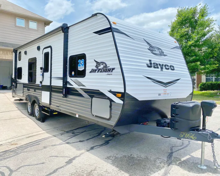 A clean, white and gray Jayco Jay Flight travel trailer, ideal for rv rental, parked on a paved driveway.. Jayco 264BH 2022