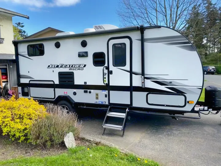 A sleek white Jay Feather Micro travel trailer parked on a driveway, ideal for RV rental adventures.. jayco Jay feather 199mbs 2022