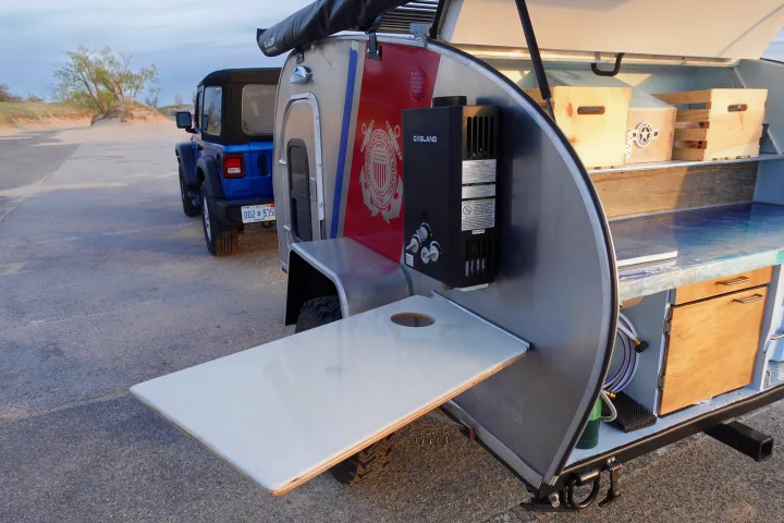 An rv rental teardrop trailer with a Coast Guard theme and an outdoor kitchen, ready for adventure with a Jeep.. Second Wind Freedom 2020