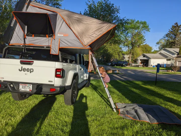 White Jeep Gladiator with rooftop tent & child climbing ladder, perfect for outdoor adventures or a unique RV rental alternative.. Jeep gladiator overland Jeep gladiator overland 2020