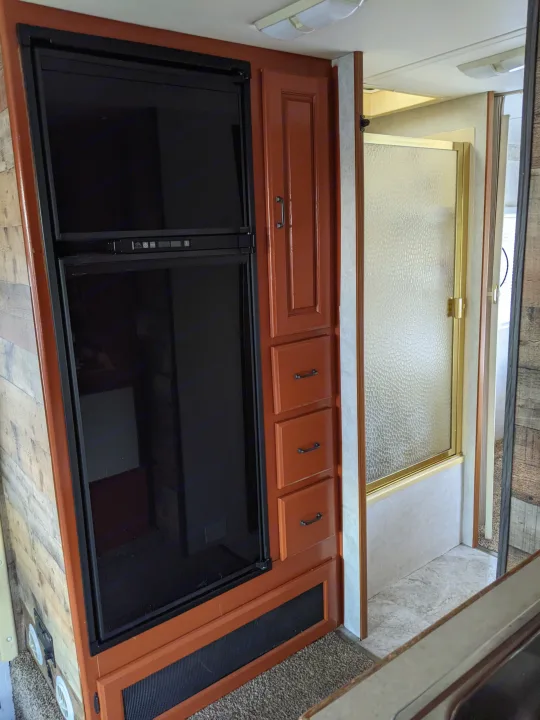 RV rental: Interior shows a compact galley with fridge, storage, and an adjacent shower stall.. Holiday Rambler Atlantis 2003