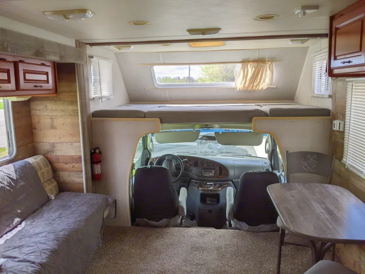 Spacious RV rental interior with cab-over bed, driver's area, sofa, and dining setup for comfortable travel.. Holiday Rambler Atlantis 2003