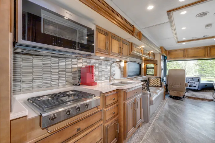 Inside a luxurious RV rental, showing a modern kitchen with stove, microwave, sink, and an inviting living space.. Other Canyon Star 2020