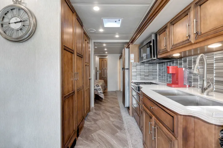Spacious RV rental interior: modern kitchen galley with sink, appliances, and cabinetry, leading to bedroom.. Other Canyon Star 2020