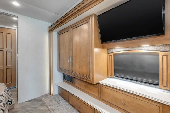 Modern rv rental bedroom with wall-mounted TV, built-in wooden storage, and illuminated window feature.. Other Canyon Star 2020