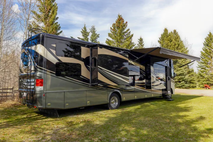Luxurious RV rental parked in a grassy area with extended awning and slide-outs, surrounded by trees.. Other Canyon Star 2020