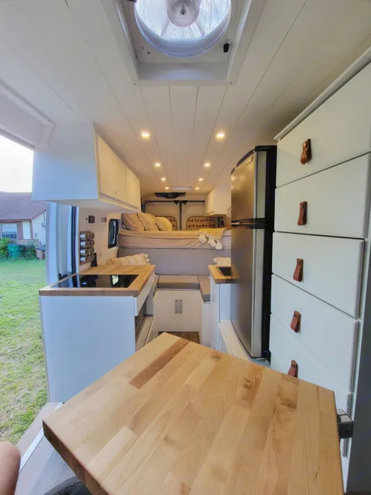 Inside a modern camper van: kitchen, bed, & storage. This RV rental offers comfy mobile living.. Other Other 2021