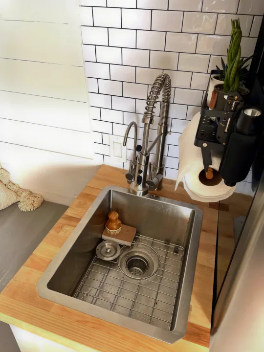 Modern RV rental kitchen: stainless sink, coil faucet, wood counter, white subway tile, and shiplap wall. Includes plants and paper towels.. Other Other 2021