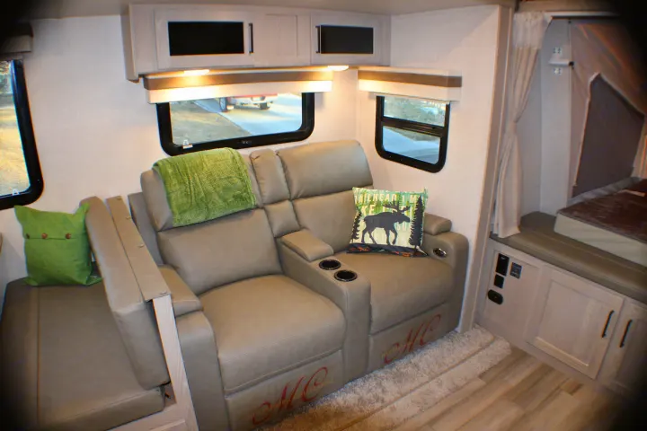 Spacious rv rental interior with light grey reclining seats, cup holders, overhead cabinets, and a pop-out bed.. Forest River Rockwood Roo 2022