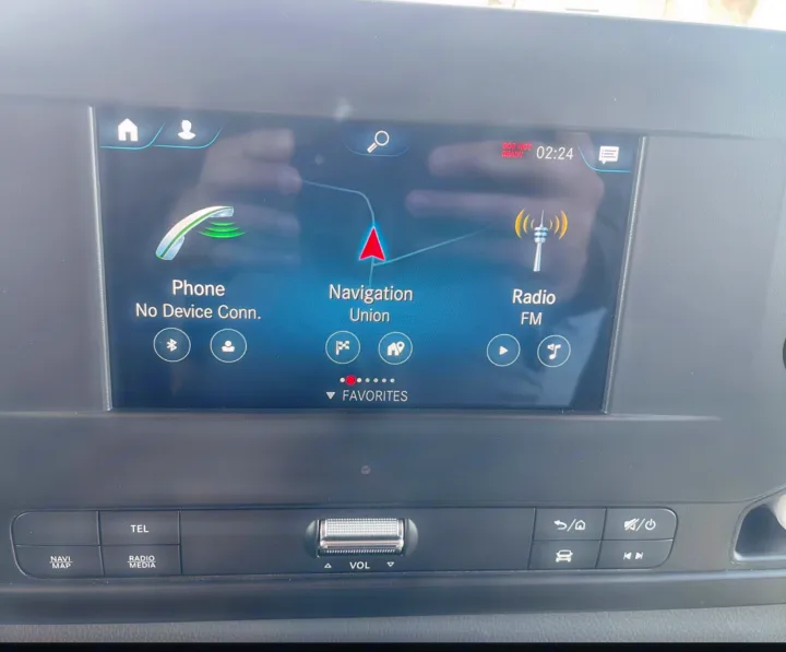 Inside an RV rental, the infotainment system displays navigation, phone, and radio options, with control buttons below.. Winnebago View 24J 2020