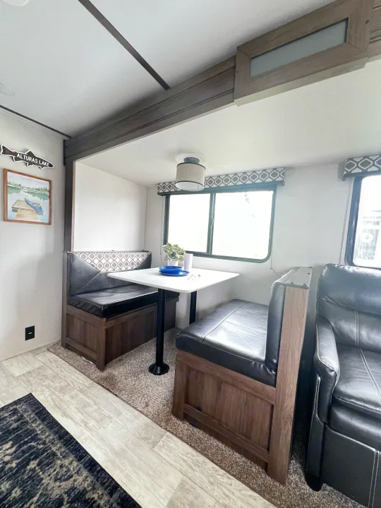 This RV rental interior features a cozy dinette with booth seating, a table, and partial views of the compact living space.. Forest River Tracer LE 2020