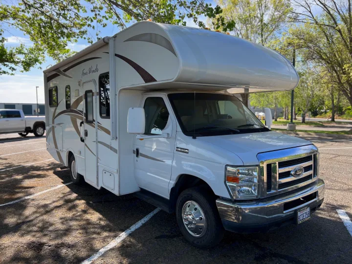 White Class C Four Winds RV rental parked outdoors under trees, ready for adventure.. Thor Four Winds 2013