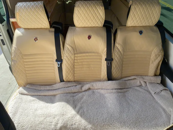 Light-colored, quilted RV rental seats with seatbelts, covered by a soft blanket. Ready for comfortable and stylish travel.. Vanworks Mercedes Benz Sprinter 2021