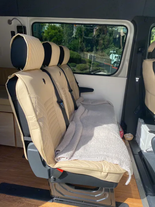 Inside an RV rental: light beige passenger seats with quilted covers, cozy blanket, and outdoor view. Ready for adventure!. Vanworks Mercedes Benz Sprinter 2021