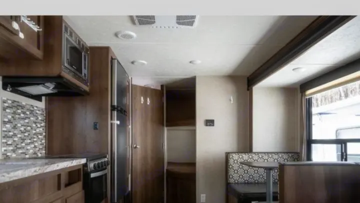 Spacious RV rental interior featuring a full kitchen with microwave, dinette, and bunk beds, ideal for travel adventures.. Shasta Oasis 2019