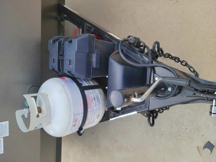 RV rental travel trailer tongue: A white propane tank, black dual battery boxes, and trailer jack are mounted.. Forest River Flagstaff 2021