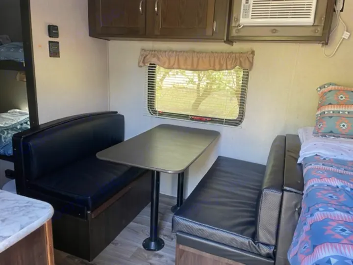 RV rental interior: A practical layout with a dark upholstered dinette, bunk beds, and a cozy sleeping area.. Keystone RV Springdale 2019