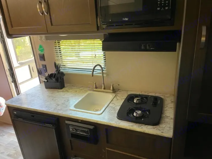 RV rental kitchen: This compact galley features a sink, two-burner stove, microwave, and mini-fridge.. Keystone RV Springdale 2019