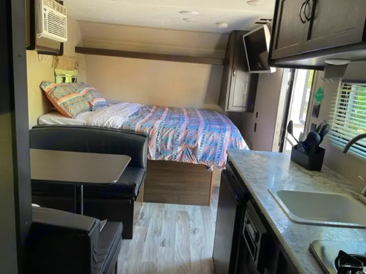 Cozy RV rental interior with a bed, dinette, and kitchen, ready for your next travel adventure.. Keystone RV Springdale 2019