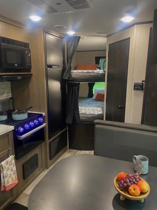 Explore this inviting RV rental interior! Features a compact kitchen, comfy bunk beds, and dining area with fresh fruit.. Jayco Jay Flight SLX 8 2022