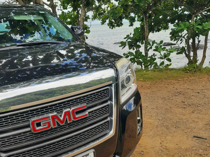 A black GMC SUV parked by calm water and trees. Perfect for exploring your rv rental route.. Gmc Terrain 2015