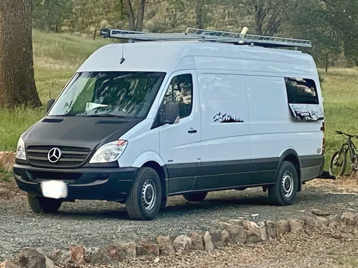 White & black Mercedes Sprinter camper van with roof rack, ready for rv rental. Parked outdoors on gravel.. Mercedes-Benz Sprinter 2013