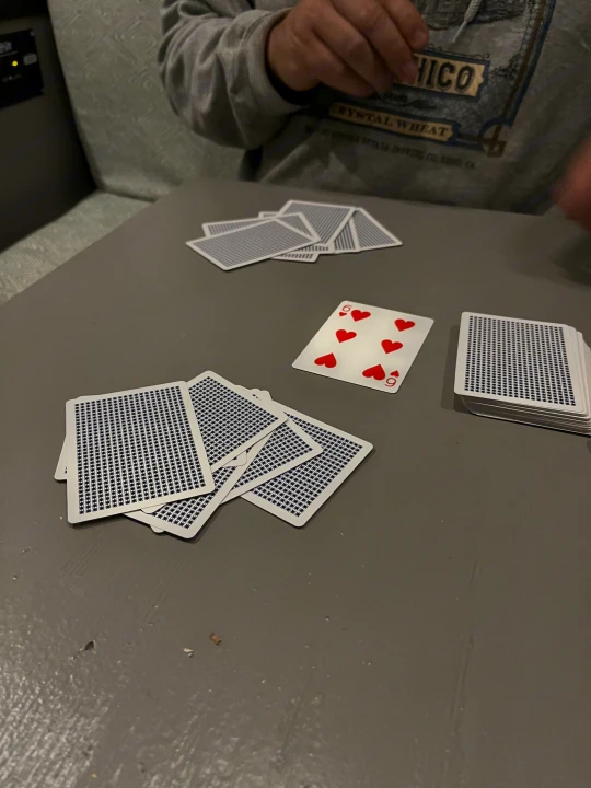 Enjoying a card game, likely poker or rummy, inside our comfortable RV rental. Features a 9 of Hearts and scattered cards.. Mercedes-Benz Sprinter 2013