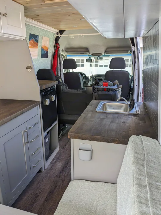 Explore this RV rental's cozy van interior: kitchenette, seating, and ample storage, extending to the driver's cabin.. Mercedes-Benz Sprinter 2013