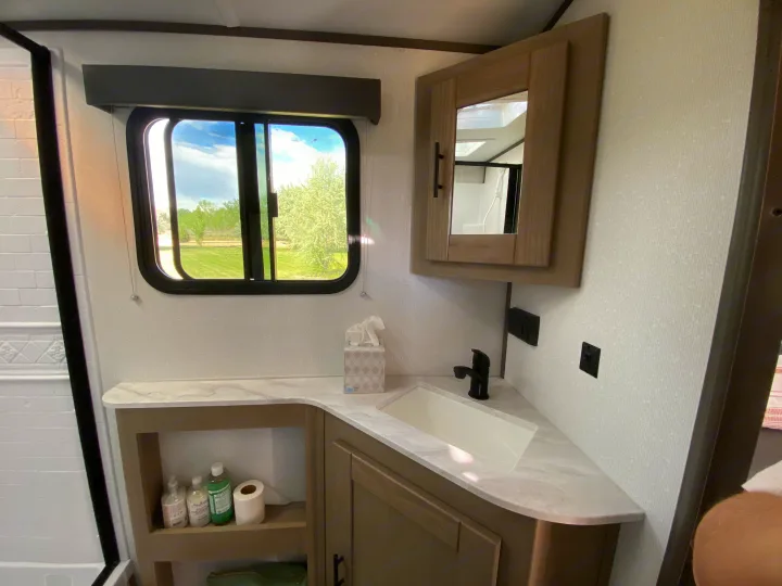 Modern RV rental bathroom with vanity, sink, mirror cabinet, and a view of nature from the window.. Cruiser RV M-277BHS 2021