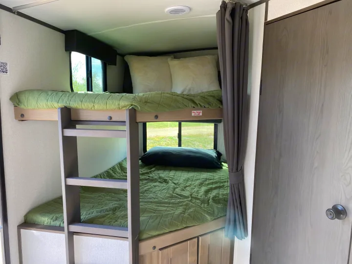 RV rental: Bunk beds with green quilts, a ladder, and outside window views. Top bunk max weight 275 lbs.. Cruiser RV M-277BHS 2021
