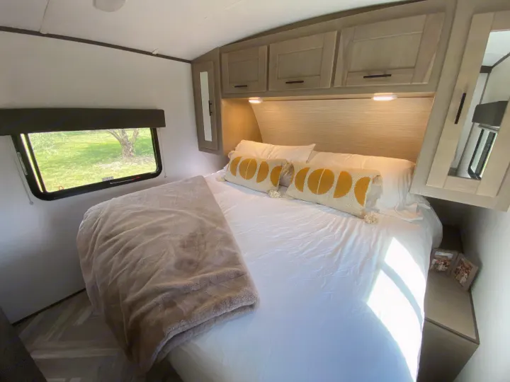 Cozy RV rental bedroom with comfortable bed, moon-pattern pillows, overhead cabinets, and scenic window view.. Cruiser RV M-277BHS 2021