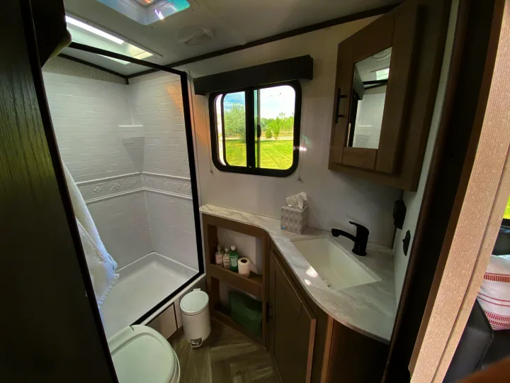 Compact and modern RV rental bathroom features a full shower, toilet, sink, and mirrored cabinet, offering comfort on the road.. Cruiser RV M-277BHS 2021